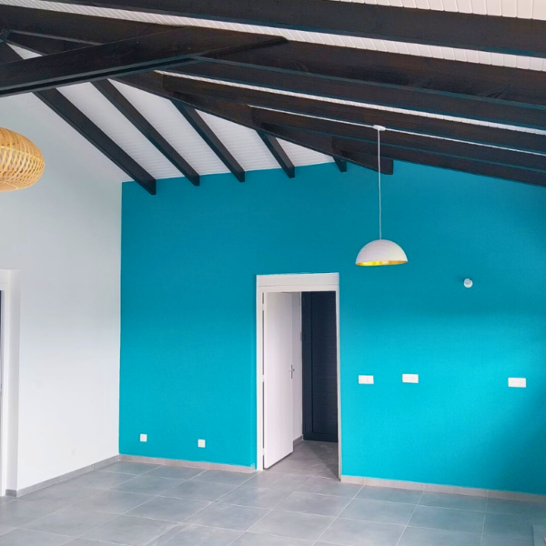 Cuisine de la Villa Firmo avec un mur bleu, une charpente en bois noir et des finitions modernes.