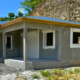 Vue extérieure de la villa Girondin terminée, avec crépi, volets roulants et toiture en tôle.